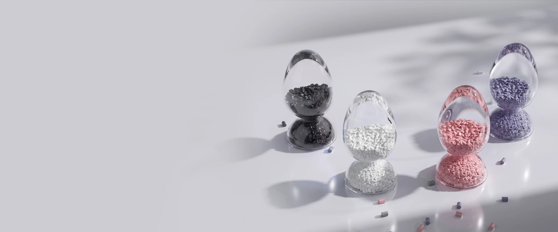 Colored plastic pellets displayed in four glass containers for pellet 3D printing