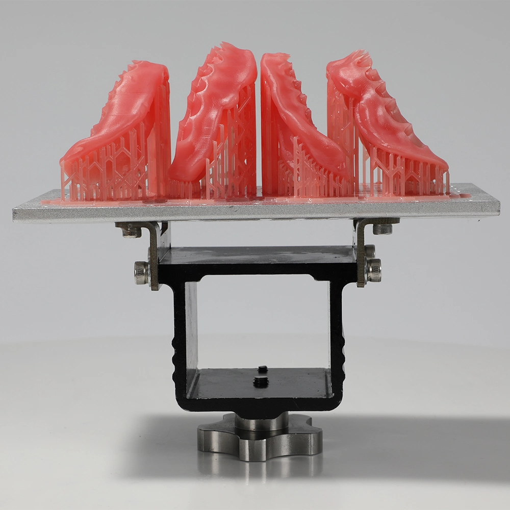 Batch of pink denture bases on a resin printing platform